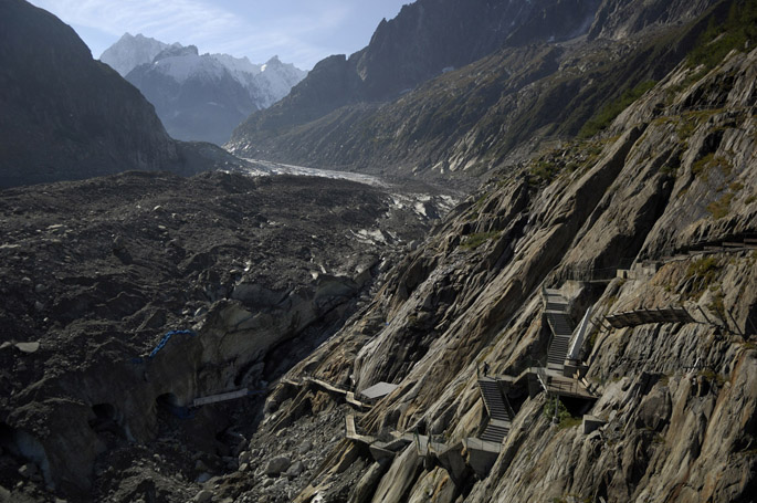 9.19.06 | A tourist walkway provides access to the Mer de Glace glacier in France.  It is a graphic indicator of the glacierâs shrinkage.  In 1988, the platform in the upper right of the image reached the ice.  Over the next 18 years the glacier receded so much that downward  extensions of the walkway were successively added to allow visitors to touch the glacier.  Note the figure on landing in the middle of the stairway for scale.